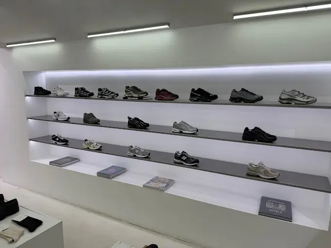 Mur de sneakers r&eacute;tro&eacute;clair&eacute; dans la boutique Ayumi Paris — s&eacute;lection premium New Balance, Asics et autres